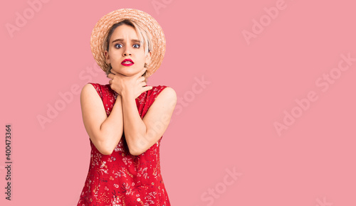 Young beautiful blonde woman wearing summer hat shouting and suffocate because painful strangle. health problem. asphyxiate and suicide concept.