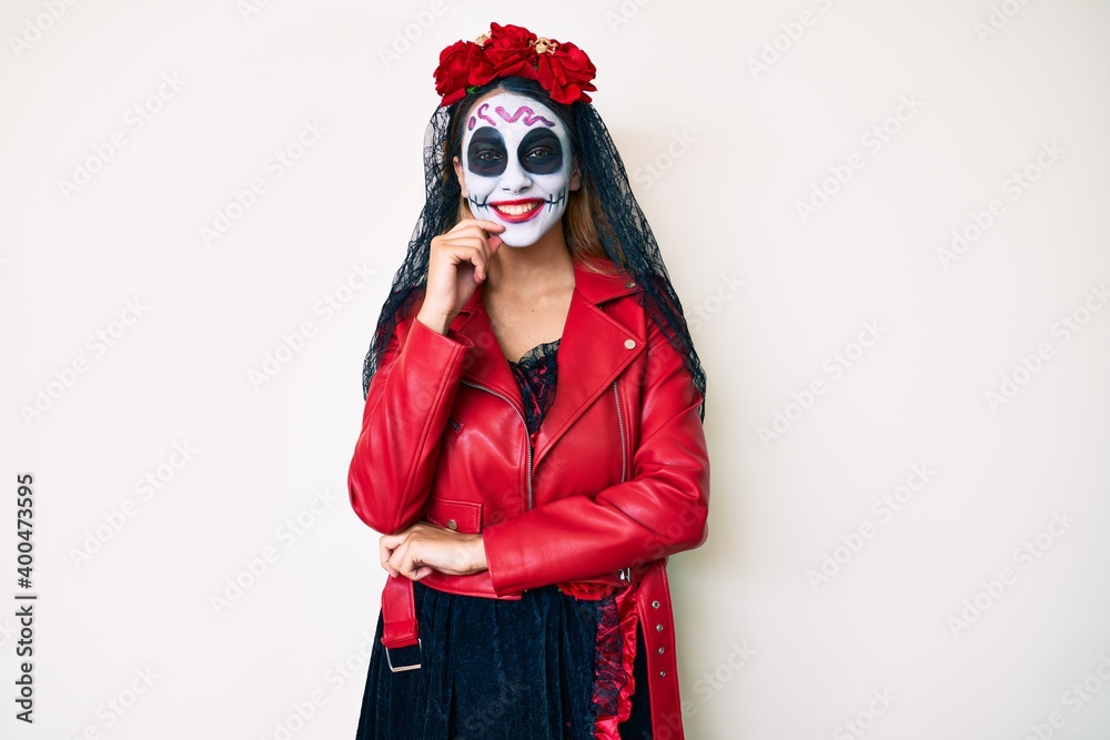 Woman wearing day of the dead costume over white looking confident at the camera smiling with crossed arms and hand raised on chin. thinking positive. Woman wearing day of the dead costume over white looking confident at the camera smiling with crossed arms and hand raised on chin. thinking positive.