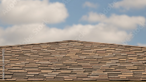Shingle roof against a cloudy blue sky