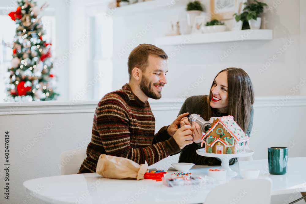 Happy Couple Decorating Christmas Gingerbread House at Home Happy Couple Decorating Christmas Gingerbread House at Home