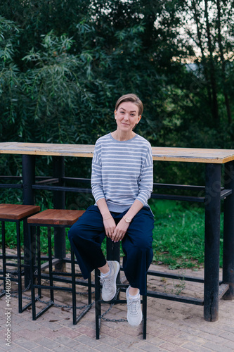 Young woman is sitting in an open cafe in a park photo