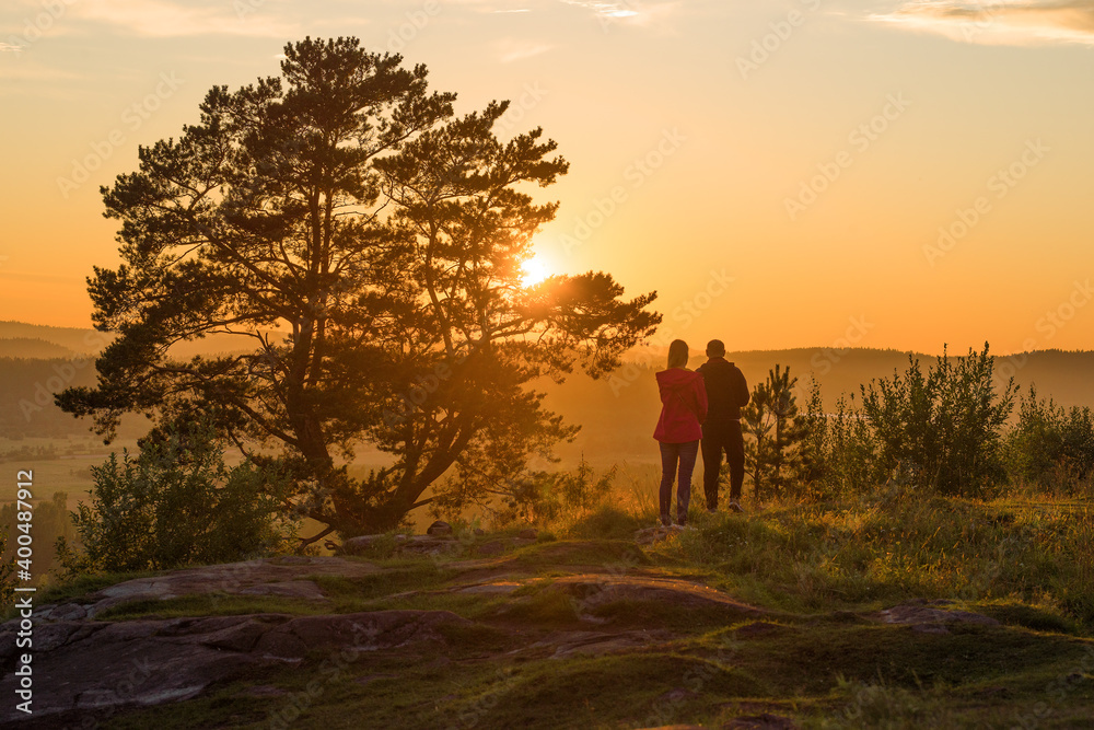 A young couple admires the summer sunset on top of Paasonwoori Mount. Sortavala, Karelia