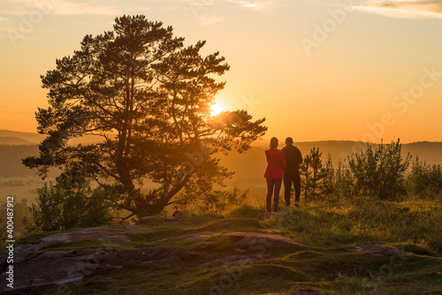 A young couple admires the summer sunset on top of Paasonwoori Mount. Sortavala, Karelia