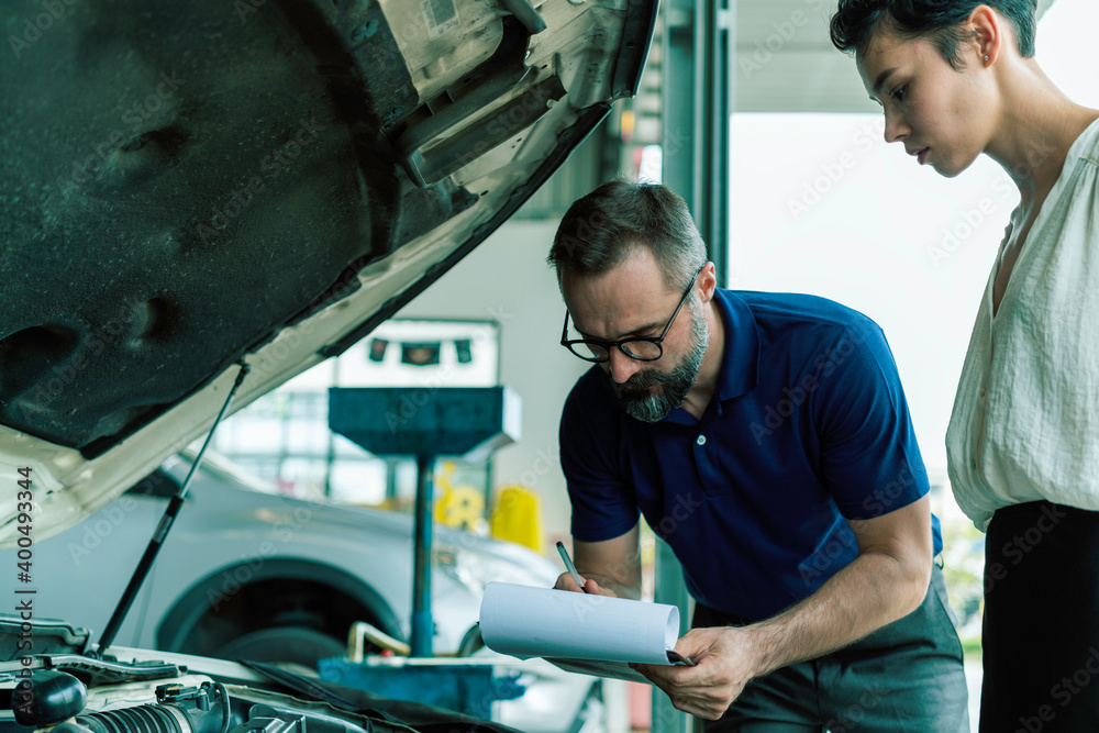 Fototapeta premium An auto mechanic talking to female customer in garage