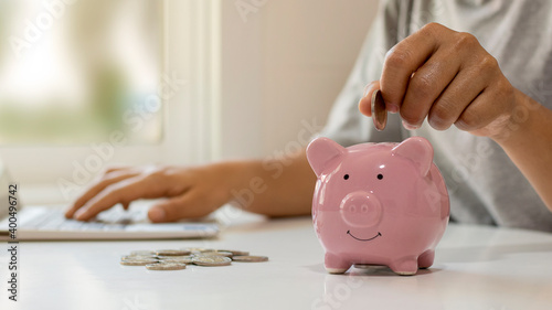 Fotografiet Women put money coins into piglets to save money and save money for future investment financial and investment ideas