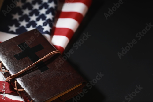 American flag and holy bible book on a mirror background. Symbol of the United States and religion. Bible and striped flag on a black background. photo