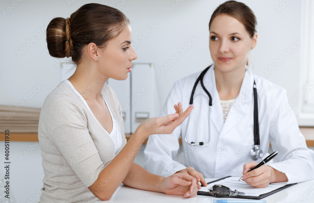 Doctor and patient are sitting and discussing health examination results in clinic office. Health care, medicine and good news concepts Doctor and patient are sitting and discussing health examination results in clinic office. Health care, medicine and good news concepts