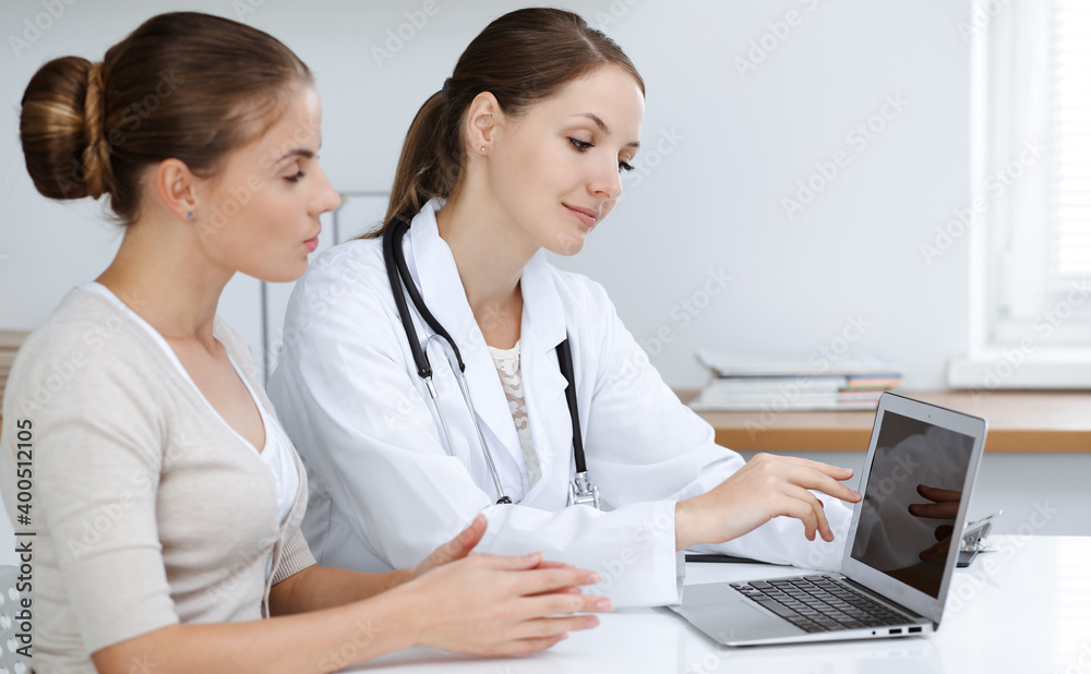 Doctor and patient are sitting and discussing health examination results while using laptop computer. Health care, medicine and good news concepts Doctor and patient are sitting and discussing health examination results while using laptop computer. Health care, medicine and good news concepts