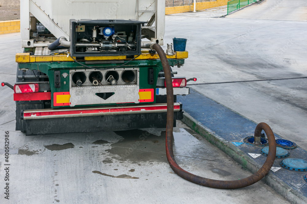 Tank truck unloading adblue with meter and by gravity in a tank on the ground, next to other diesel discharge ports.