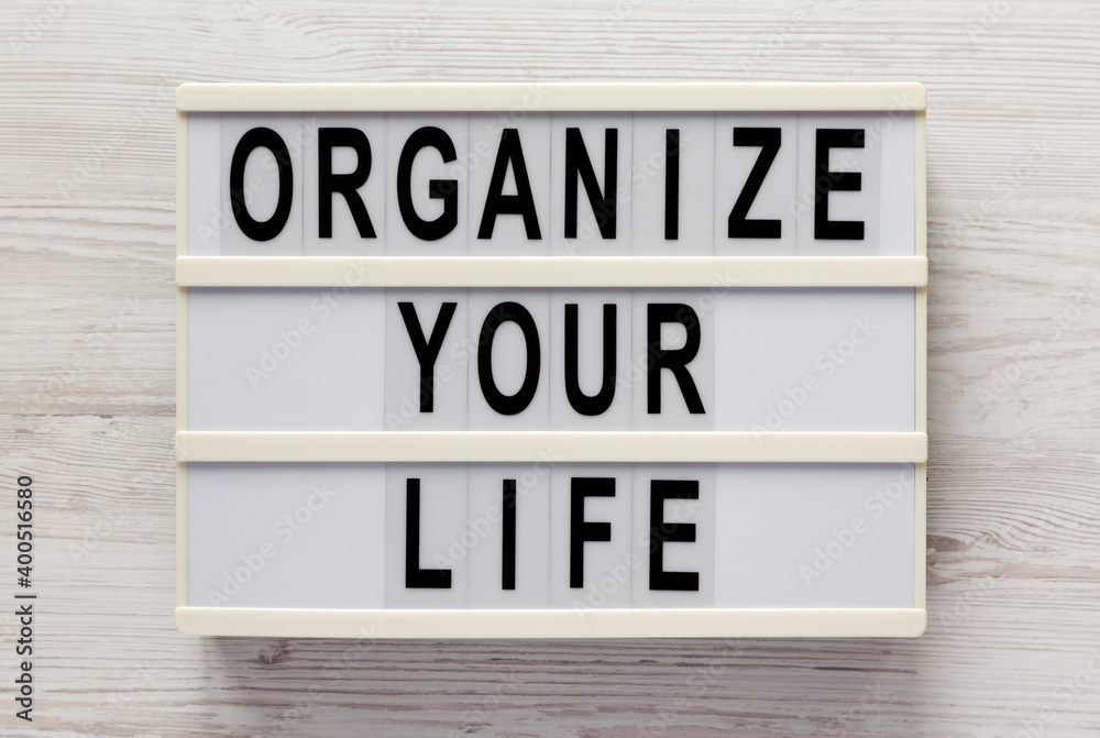 'Organize your life' on a lightbox on a white wooden background, top view. Flat lay, overhead, from above.