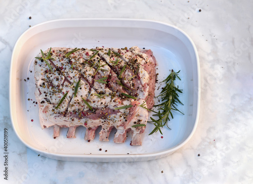 Raw rack of pork with spices in the baking dish. Top view.