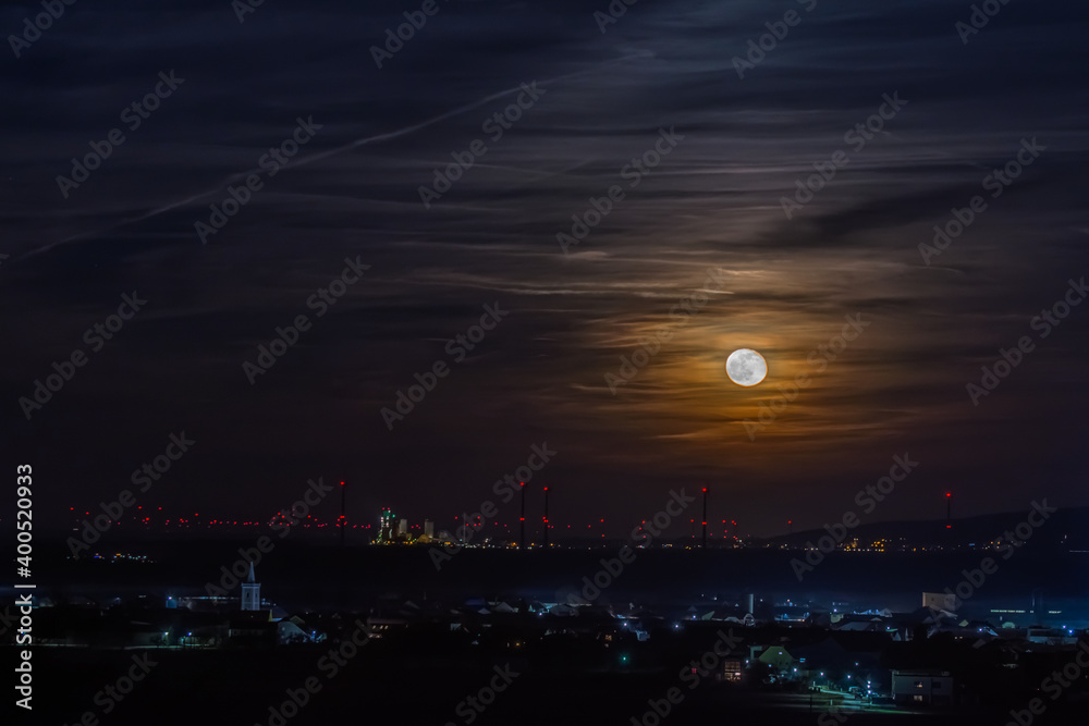 shining moon on the sky with clouds and illuminated city