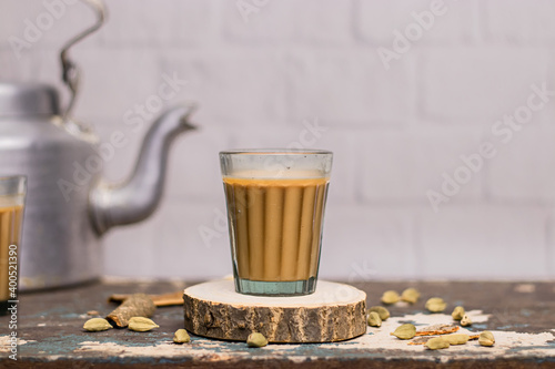 Indian chai in glass cups with metal kettle and other masalas to make the tea. 