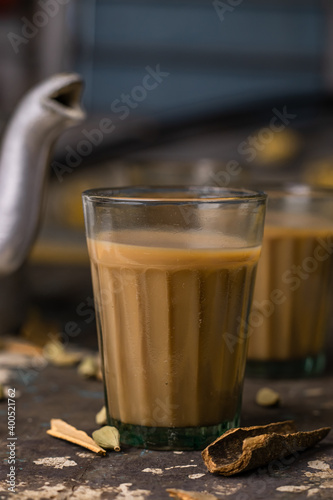 Photography Indian chai in glass cups with metal kettle and other masalas to make the tea