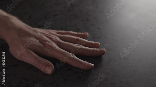 young man hand finger tap on terrazzo countertop with dim light