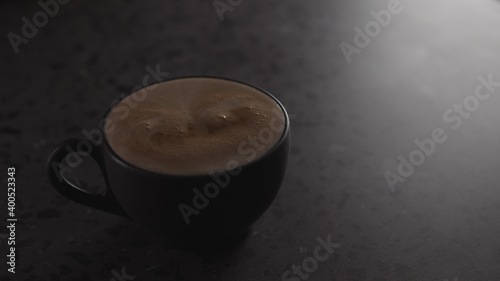 hot chocolate into black cup on concrete countertop with copy space under dim light