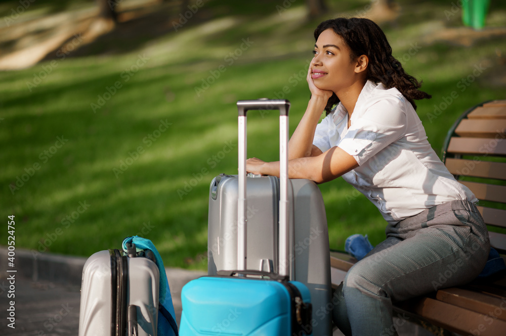 Woman with suitcase sitting on the bench in park Woman with suitcase sitting on the bench in park