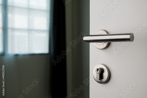 The white door has a steel handle and a keyhole. Turn into the living room of the house photo