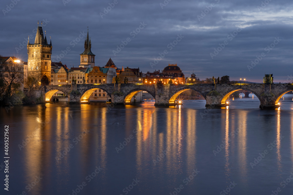 Charles Bridge on the Vltava River at sunset and colorful clouds and lights on the bridge in the early evening in the center of Prague