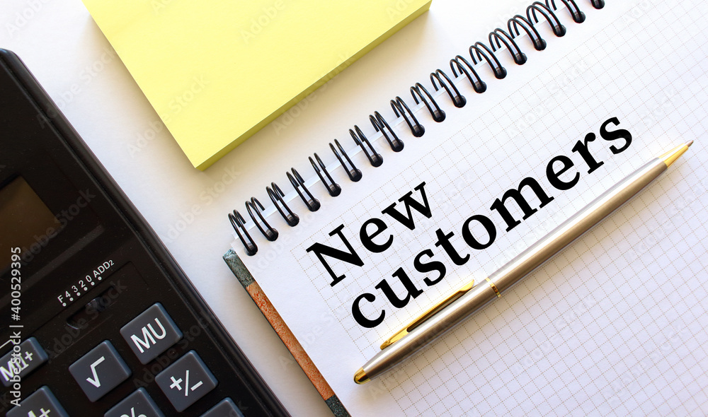 Notepad with text NEW CUSTOMERS, next to it lies a calculator. Business concept. Notepad with text NEW CUSTOMERS, next to it lies a calculator. Business concept.