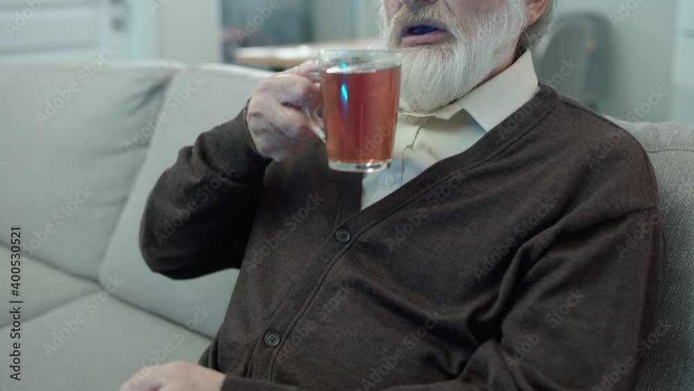 Retired man drinking tea at home watching tv in free time, elderly entertainment Retired man drinking tea at home watching tv in free time, elderly entertainment
