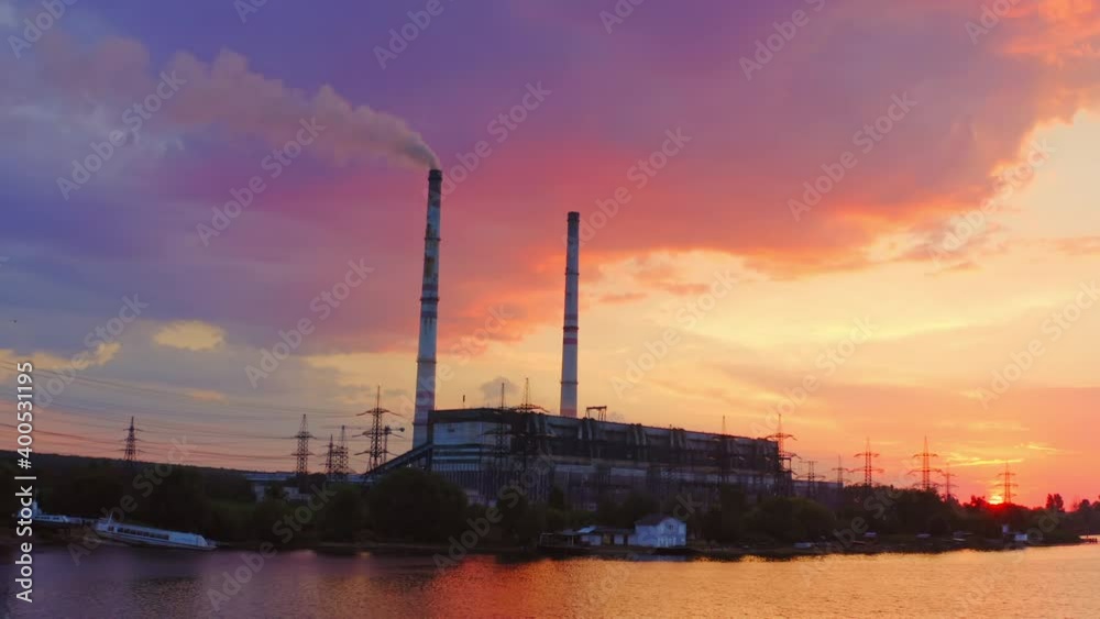 Industrial area at sunset. Factory near the river on the beautiful pink sky. Harmful manufacture with smoke goes from industrial pipe in the evening. Industrial area at sunset. Factory near the river on the beautiful pink sky. Harmful manufacture with smoke goes from industrial pipe in the evening.