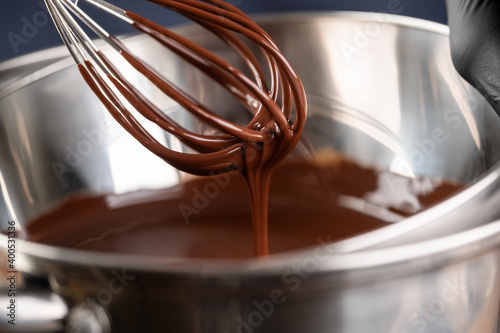 Melted chocolate drips from the whisk into a metal bowl. Homemade chocolate. Confectionery chocolate