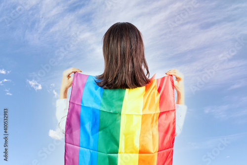 Woman with the rainbow flag with the blue sky in the background