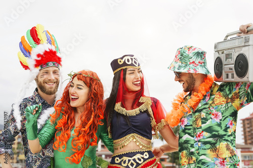 Happy friends celebrating carnival party outdoor - Young crazy people having fun wearing costumes listening music with vintage boombox stereo - Youth holidays culture lifestyle concept