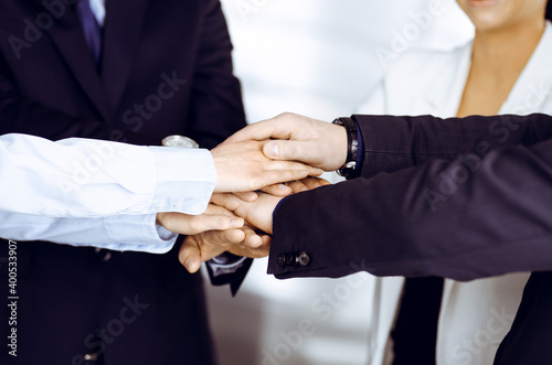 Group of unknown businesspeople are joining hands in a modern office. Unknown businessmen are making circle with their hands. Concept of trust and support in a business
