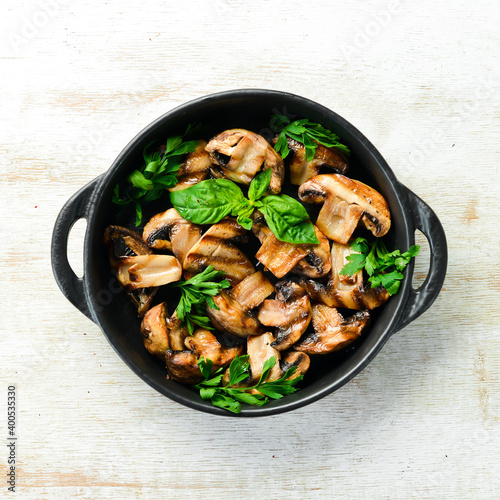 Food. Grilled mushrooms with basil on a black stone plate. Top view. Free space for your text.