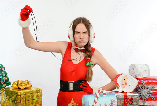 A young girl dresses up in red and wants to hear 
Christmas music. She wears headphones on her 
head and is disturbed that she has no power connection 
and no music. photo