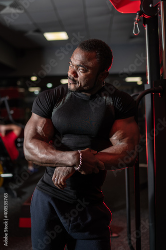 Portrait of african american fitness trainer looks at side on modern sport equipment background. Healthy lifestyle concept.