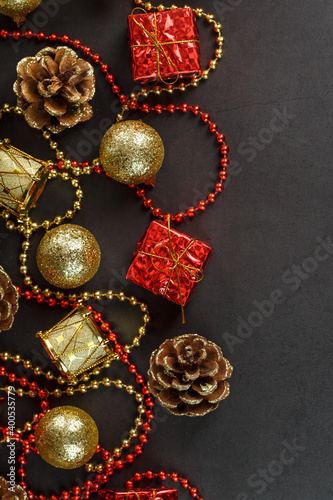 Christmas decorations in gold and red on a black background with free space. View from above.