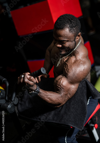 Fit young black man lifting barbells doing workout at a gym. Sport, fitness, weightlifting, bodybuilding, training, athlete, workout exercises concept. View from the side.