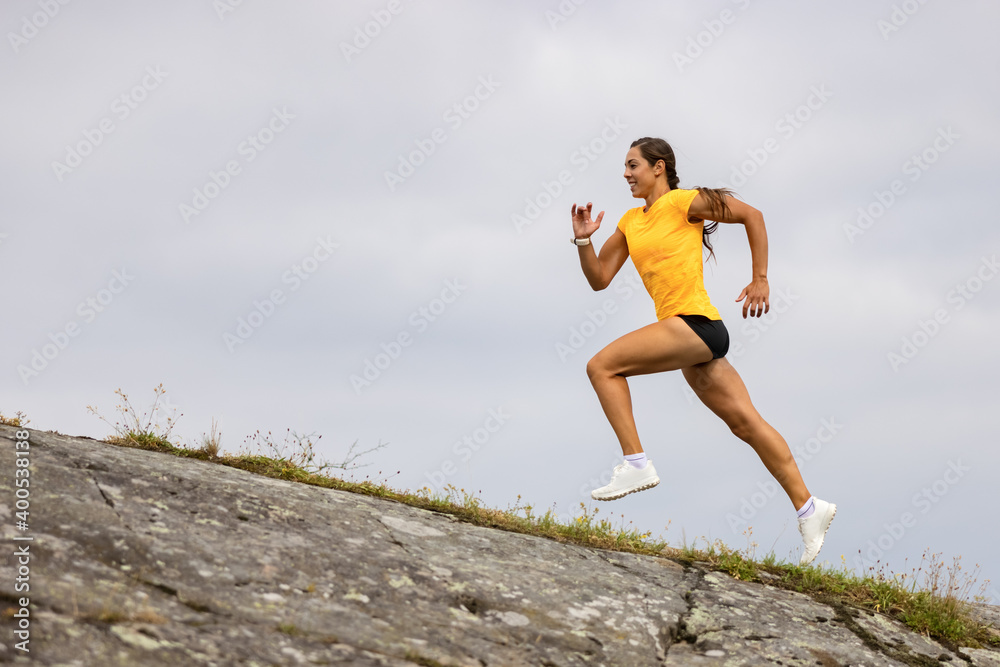 Side view of fitness woman doing high-intensity running on mountainside by the sea Side view of fitness woman doing high-intensity running on mountainside by the sea