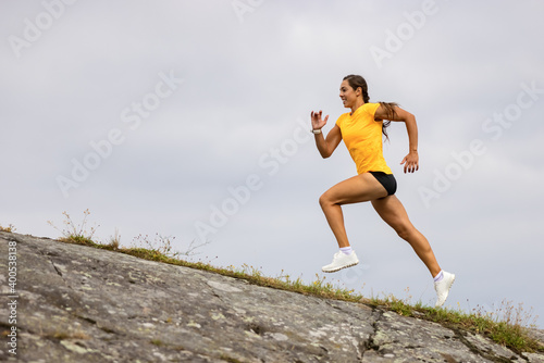 Side view of fitness woman doing high-intensity running on mountainside by the sea