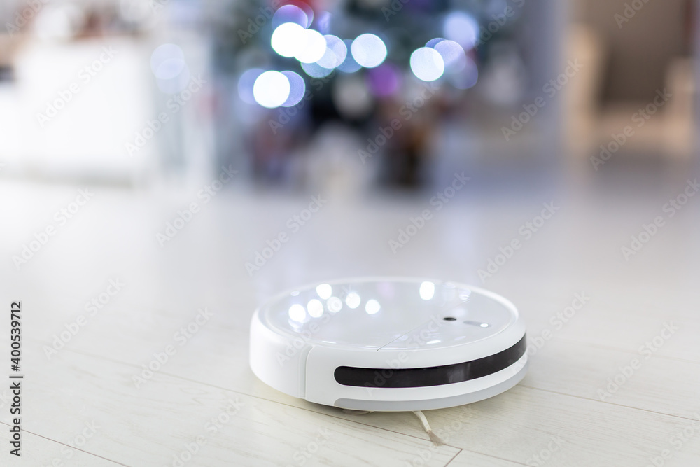 Robotic vacuum cleaner hoovering the floor at christmas tree Robotic vacuum cleaner hoovering the floor at christmas tree