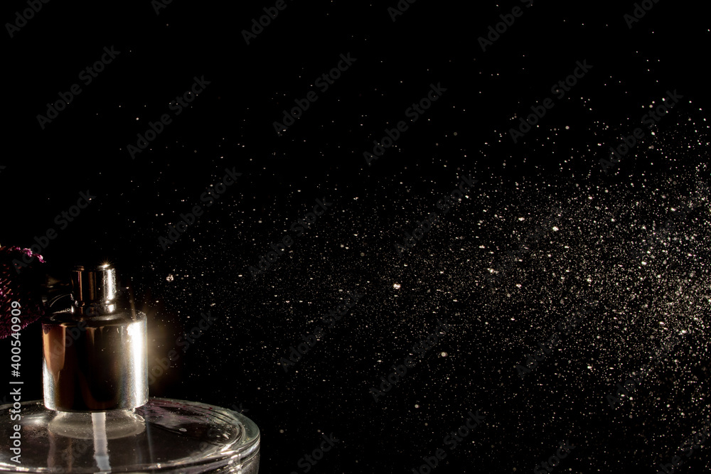 Spraying perfume bottle glass on a black background Spraying perfume bottle glass on a black background
