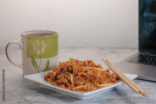 Laptop computer or notebook, char kuew tiaw and cup of coffee on working table with copy space . photo