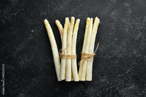 Raw white fresh asparagus on a black stone background. Healthy food. Top view. Free space for your text.