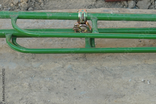 A pipe clamps catch on a green steel scaffolding in the civil construction area .