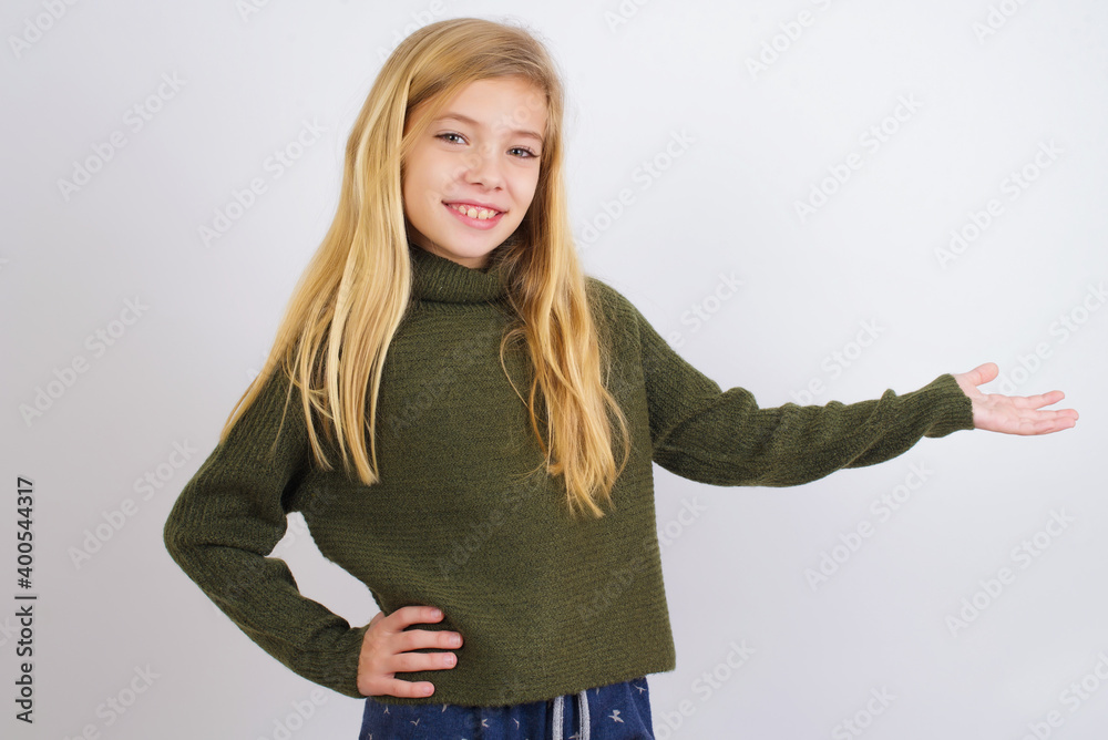 Caucasian kid girl wearing green knitted sweater against white wall feeling happy and cheerful, smiling and welcoming you, inviting you in with a friendly gesture Caucasian kid girl wearing green knitted sweater against white wall feeling happy and cheerful, smiling and welcoming you, inviting you in with a friendly gesture