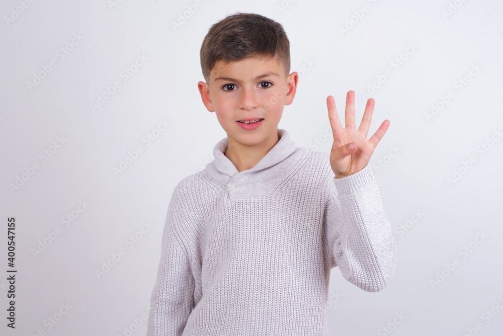 Cute Caucasian kid boy wearing knitted sweater against white wall showing and pointing up with fingers number four while smiling confident and happy. Cute Caucasian kid boy wearing knitted sweater against white wall showing and pointing up with fingers number four while smiling confident and happy.