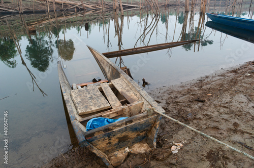 Flooded boat in water. Traditional old wooden boat for fishing. Nam Theun river, Thalang, Thakhek, Laos  photo