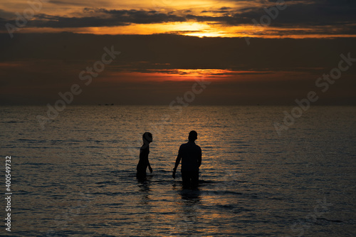 Silhouette couple standing midth of sea in the warm light evening time
