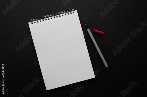 white notebook and red pencil on black background, isolated. taking note. blank paper. new year's resolution, goals. 2021. copy space. 