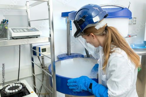 Kryokonservierung von Zellen und Gewebe im Stickstofflagertank, Biotechnologin öffnet Flüssigstickstoff Behälter.  photo