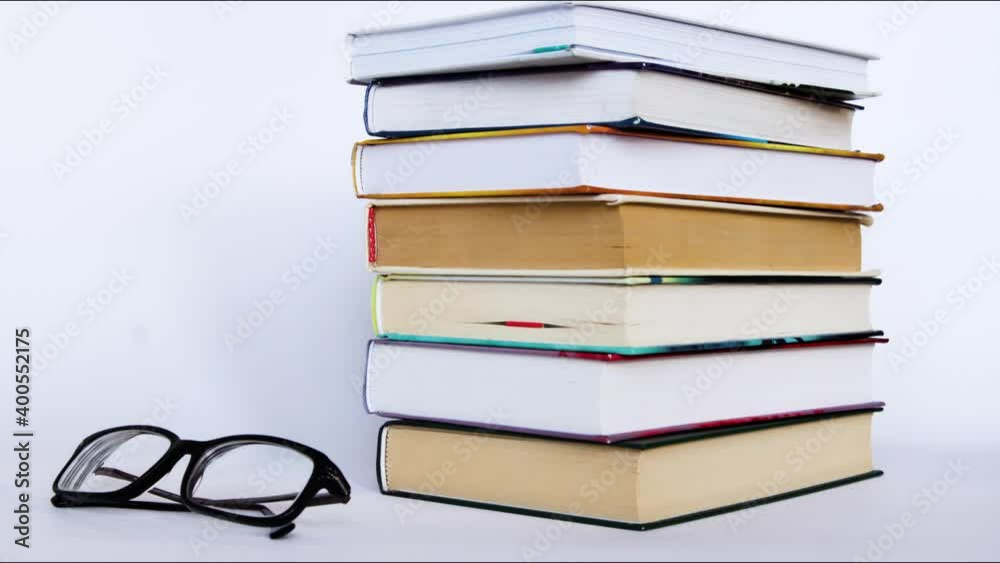 A stack of books and glasses on a white background. Stop motion books.