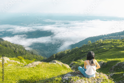 Female person sits and enjoys the views of stunning landscape above the clouds in Gomismta. Georgia travel destination